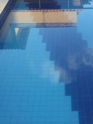 Antes: piscina com a faixa de pastilha azul-escura no fundo e a água refletindo o céu