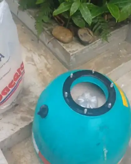 Filtro de piscina aberto, pronto para a areia nova, ao lado do saco de areia