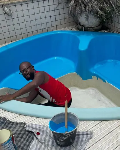 Reforma de piscina de fibra: o profissional da Oliveira Piscinas pintando o fundo, com metade já azul